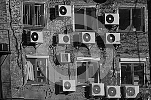 Black and white air conditioners on the brick wall