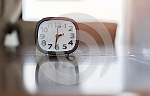 Black and white alarm clock on wooden table with blurred backgroundBlack and white alarm clock on wooden table with blurred
