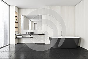 Black and white bathroom with sink and bathtub on black tiled floor