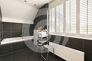 a black and white bathroom with a tub and window