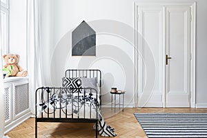 Black and white bed in teenager`s bedroom interior with plush toy and poster on the wall