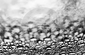Black and white big raindrops on glass surface, clear below and blurred up in the picture