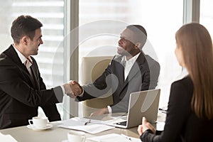 Black and white businessmen handshaking at meeting, making succe
