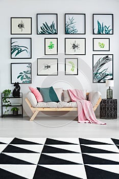 Black and white carpet with geometric pattern placed on the floor in bright sitting room interior with wooden lounge with green an