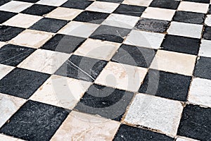 Black and white checkerboard tiles, old with scratches and scuffs.