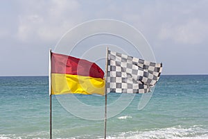 Black and white checkered flag and surf lifesaving flag on beach photo