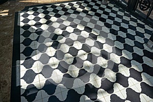 Black and white checkered floor grunge tiles marble surface at public place with interiors and people legs