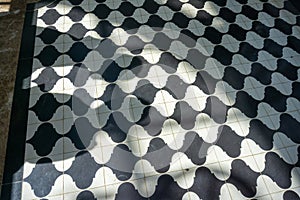 Black and white checkered floor grunge tiles marble surface at public place with interiors and people legs