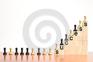 Black and white chess pawns lined up on a staircase made of wooden blocks, with the word