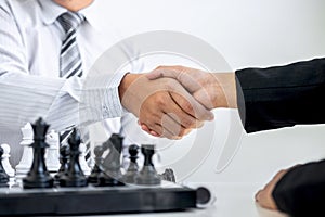 Black and White chess with player, Businessman and Businesswoman shaking hands after end game of thinking strategy to moving chess