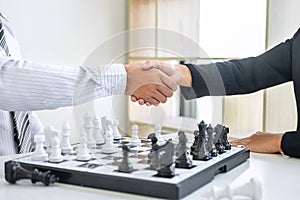 Black and White chess with player, Businessman and Businesswoman shaking hands after end game of thinking strategy to moving chess