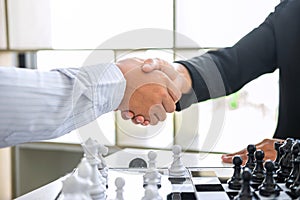 Black and White chess with player, Businessman and Businesswoman shaking hands after end game of thinking strategy to moving chess