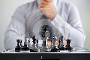 Black and White chess with player, Hands of businessman thinking to moving chess figure in competition and planning strategy to