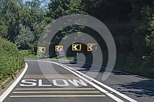 Black and white chevrons, a double white line and a skid risk warning sign tell drivers to slow down because there is danger ahead