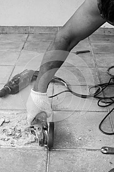 Black and white circular saw. A man sawing ceramic tiles. Worker sawing a tile on a circular saw. Construction works. Selective