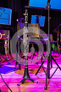 A black and white clarinet is on a stand in front of a blue sign photo