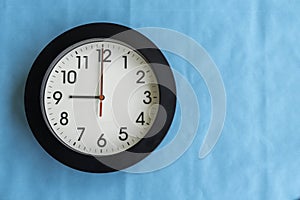 A black and white clock on a blue wall
