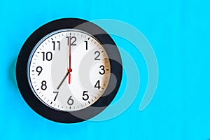 A black and white clock on a blue wall