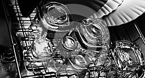 Black and white close-up image of whiskey Old Fashioned or Rocks glasses along with shot or shooter glasses on a dish drainer in t