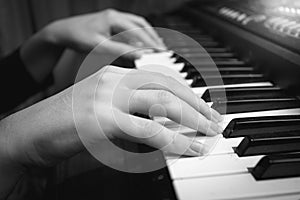 Black and white closeup of female hands on digital piano keyboard