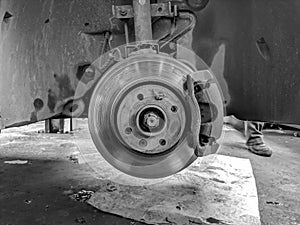 Black and white closeup of metallic disk of a car with no tires in a mechanics shop, waiting for tire replacement and repairing