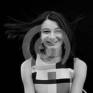 Black and white closeup portrait of a beautiful happy smiling young girl, wind blows her hair