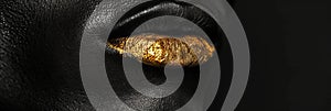 Black and white closeup shot of an African American man face with metallic gold lips, showcasing the intricate details