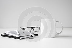 Black and white coffee mug mock up with notebooks, pen and eyeglasses