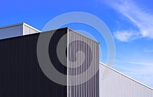 Black and white corrugated metal factory buildings against blue sky