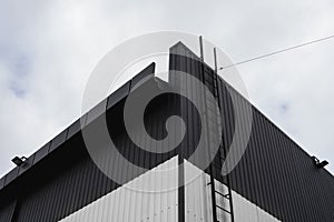 Black and white Corrugated metal sheet texture surface on a building wall with a cloudy sky. Galvanize steel background.