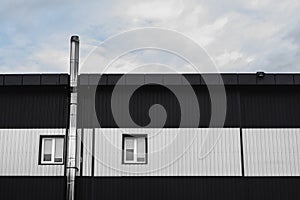 Black and white Corrugated metal sheet texture surface on a building wall with windows. Galvanize steel background.