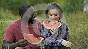 Black and white couple enjoying themselves and eating delicious watermelon
