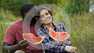 Black and white couple enjoying themselves and eating delicious watermelon
