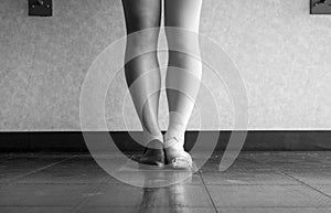 Black and white Dancer standing in parallel position at the barre, half dress in Jazz dance attire and half in ballet attire