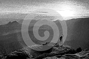 Black and white dashed retro sketch. Man stands on the peak of rock watch to Sun. Beautiful moment the miracle of nature