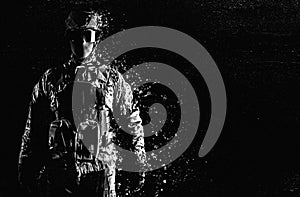 Black and white dissolving soldier in tactical clothing on black background