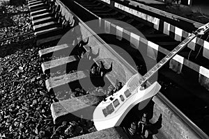 Black and white electric guitar on the railroad tracks and stone