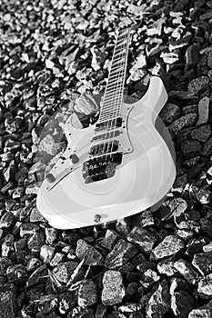 Black and white electric guitar on the railroad tracks and stone