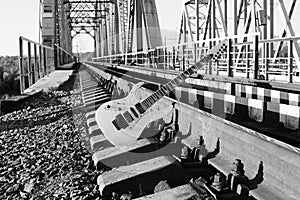 black and white electric guitar on the railroad tracks and stones