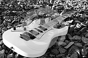black and white electric guitar on the railroad tracks and stones