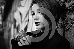 Black and white female portrait of young girl with short blonde hair near the wall with graffiti. Youth culture, street