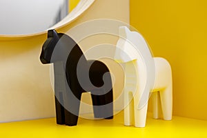 Black and white figurines of horses stand on a shelf on a table on a yellow background