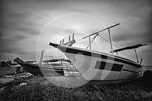 Black and white fisherman boat on the shore with soft clouds background