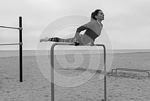 Black and white fitness woman doing hand stand exercises on callisthenics outdoor gym bars.Beach workout, street sports training