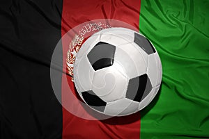 Black and white football ball on the national flag of afghanistan