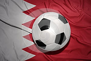 Black and white football ball on the national flag of bahrain
