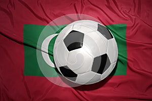 Black and white football ball on the national flag of maldives