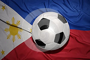 Black and white football ball on the national flag of philippines