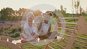 Black And White Girl Sitting On Wooden Slide. Girls Smiling. Cheerful Children.