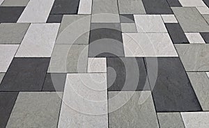 Black, white and gray concrete tiles of different shapes in an outdoor pavement